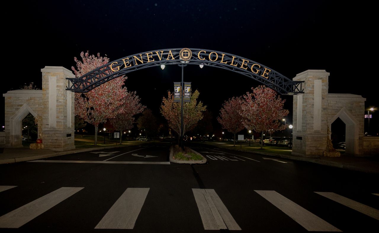 Photographed is a picture of the arch entrance of Geneva College's campus at night. 