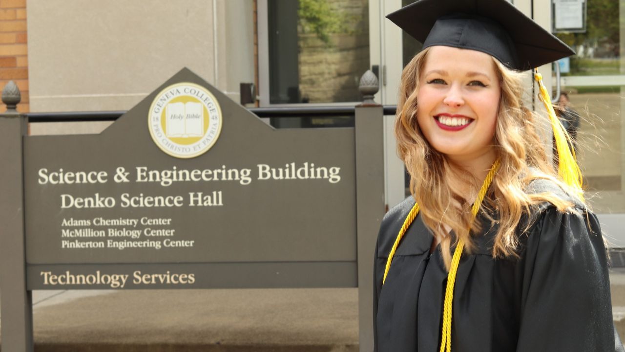 Lois Montgomery, Geneva graduate of 2019, is pictured next to the Science and Engineering Building sign on campus in her graduation cap and gown.