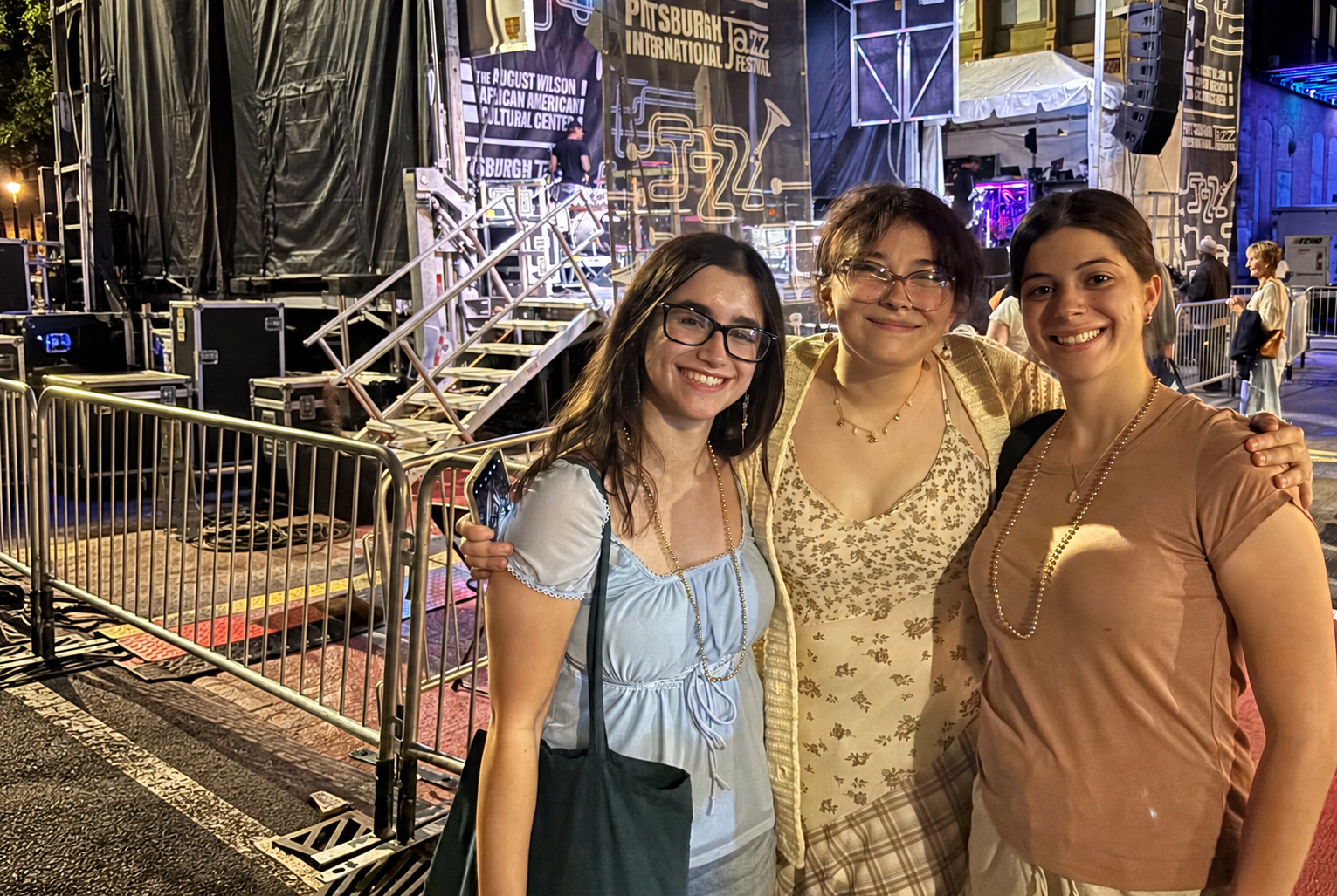 Three Female students standing in front of the Jazz festival stage.