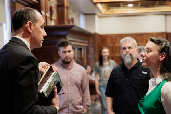Male professor holding books while speaking to a student