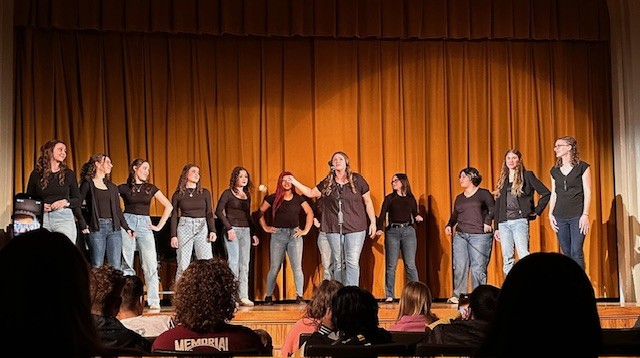 Grace Notes group singing in John White Chapel, wearing jeans and black shirts.