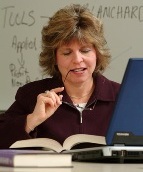 Photo of a student researching with books and a laptop