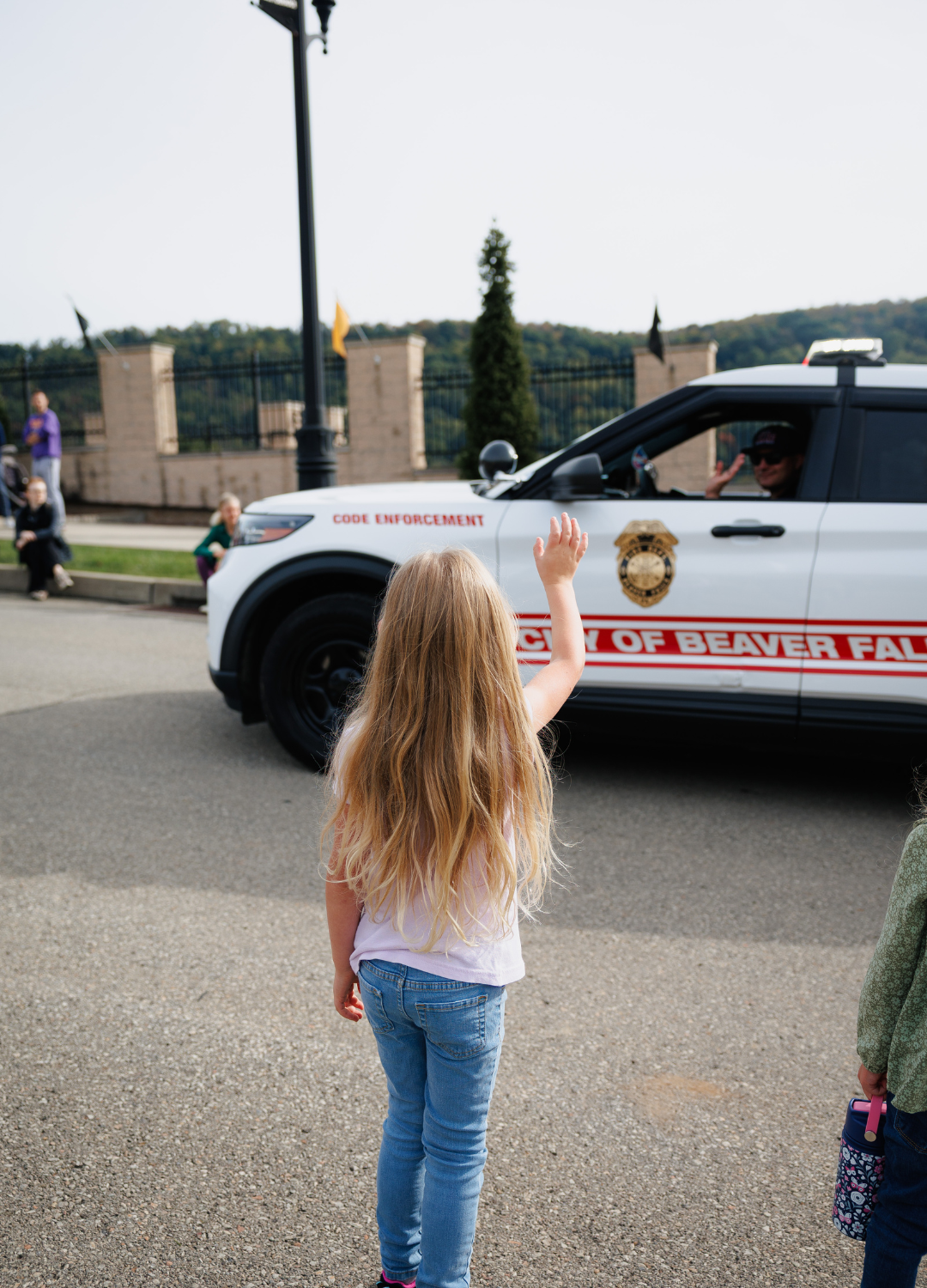 A Child Waving to a Beaver Falls Police Officer in the Parade