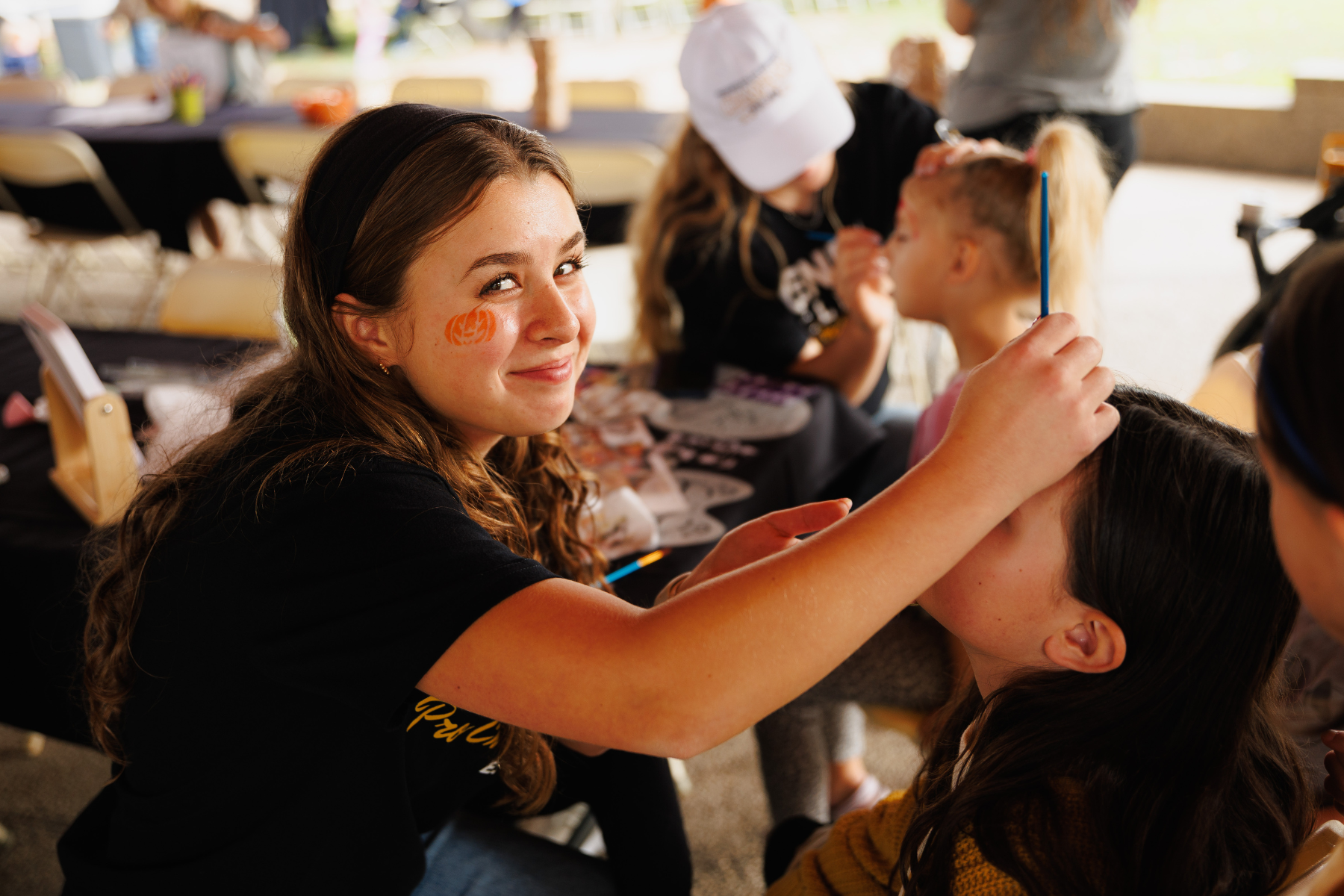 A Volunteer Painting Faces During Family Fun Event